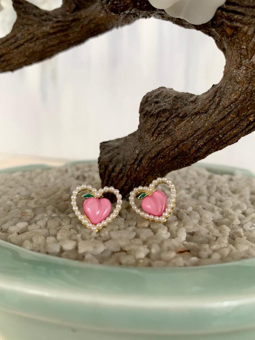 Pink peach fruit shape in hollow white pearls heart shape stud fashion jewelry earrings in front of tree - Roulette Safari