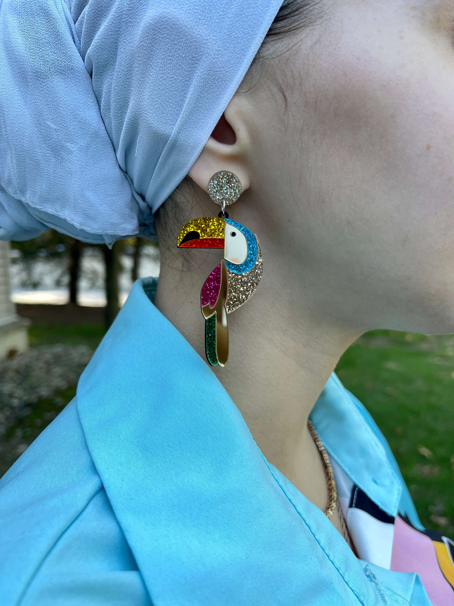 Close up to ear with acrylic glitter gold green pink turquoise red yellow tropical toucan parrot shape dangle drop fashion jewelry earrings - Roulette Safari