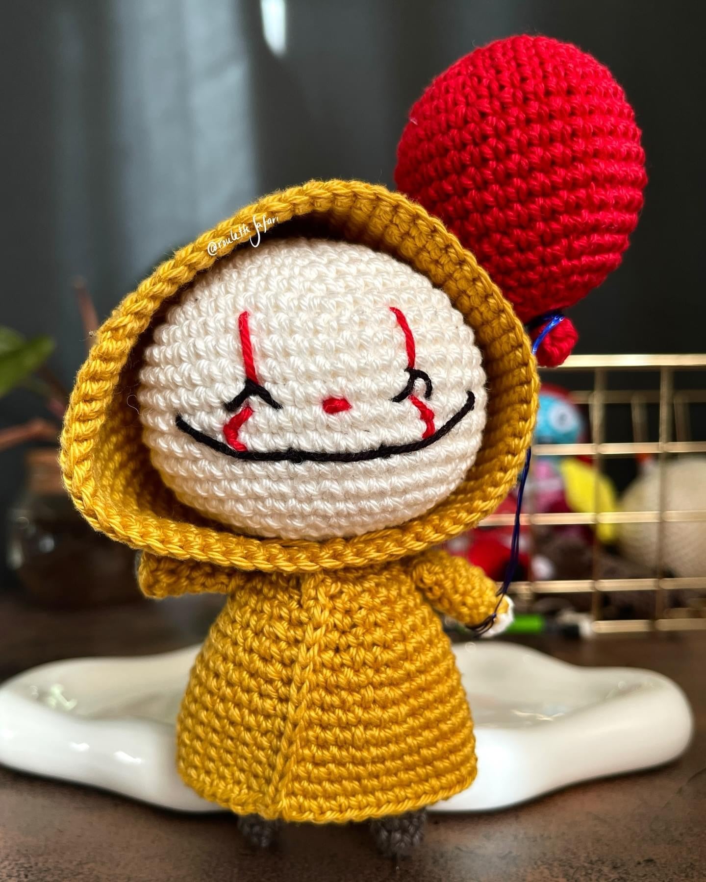 Crochet Amigurumi creepy clown with yellow raincoat holding a red balloon plush toy