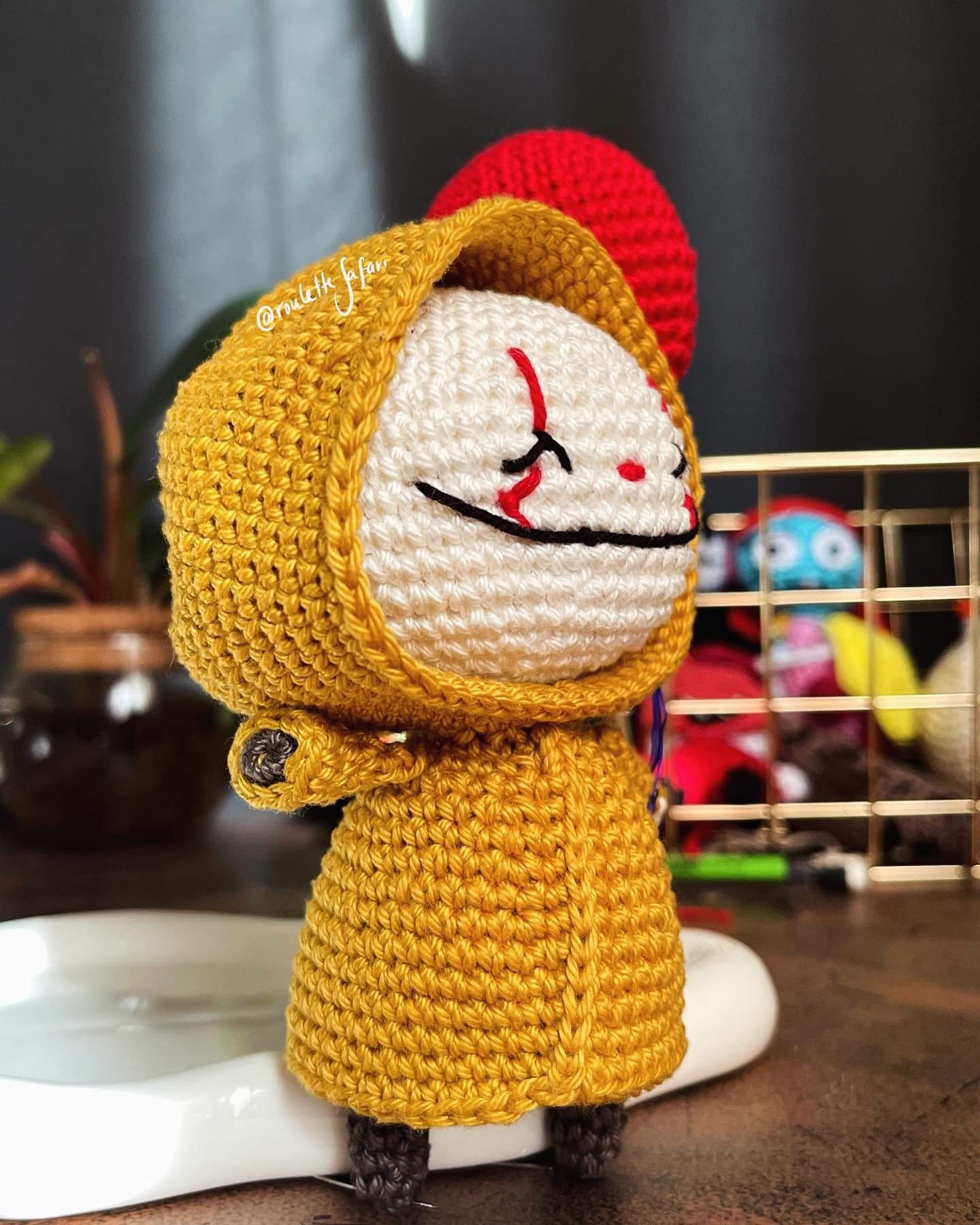 Crochet Amigurumi creepy clown with yellow raincoat holding a red balloon plush toy