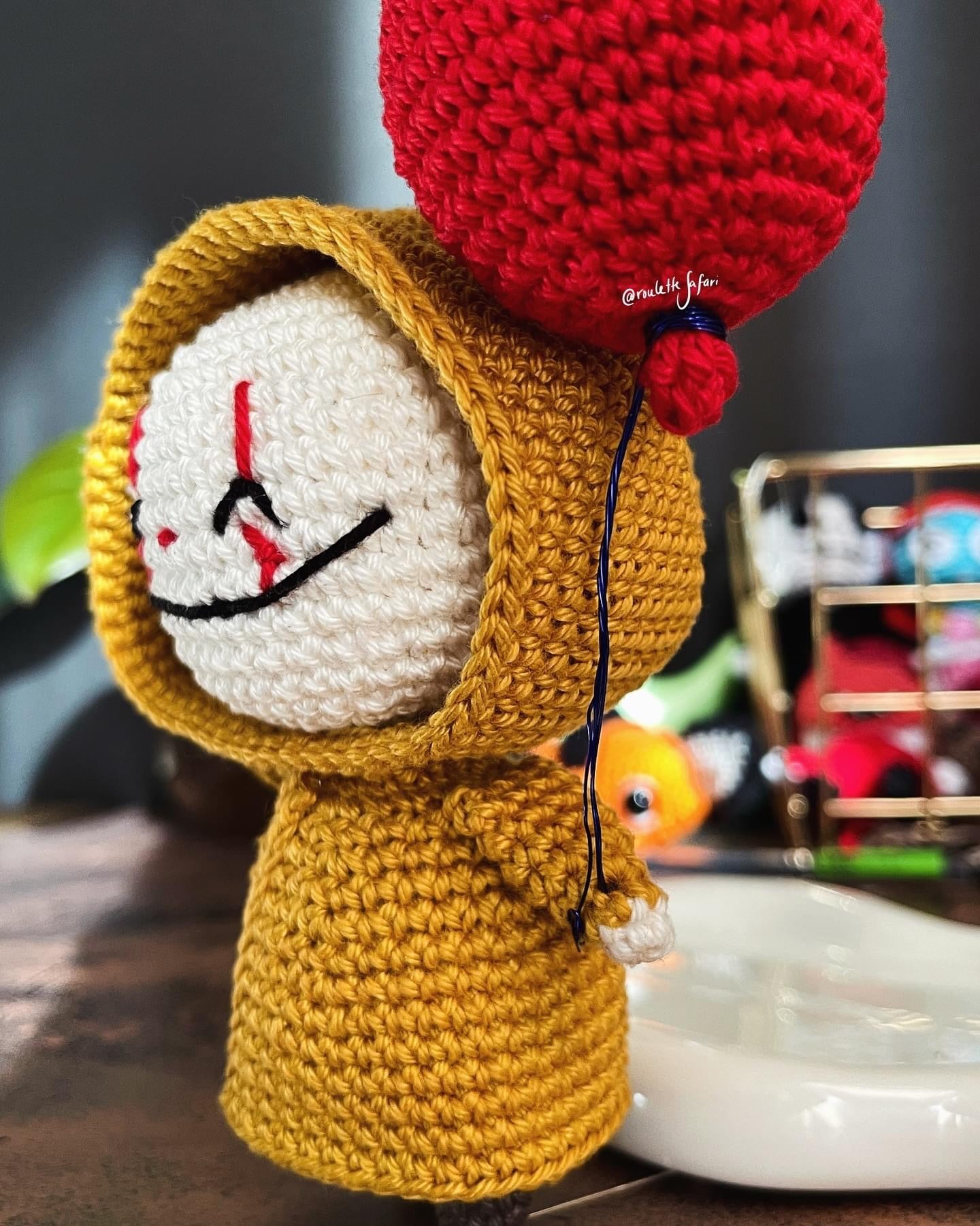 Crochet Amigurumi creepy clown with yellow raincoat holding a red balloon plush toy