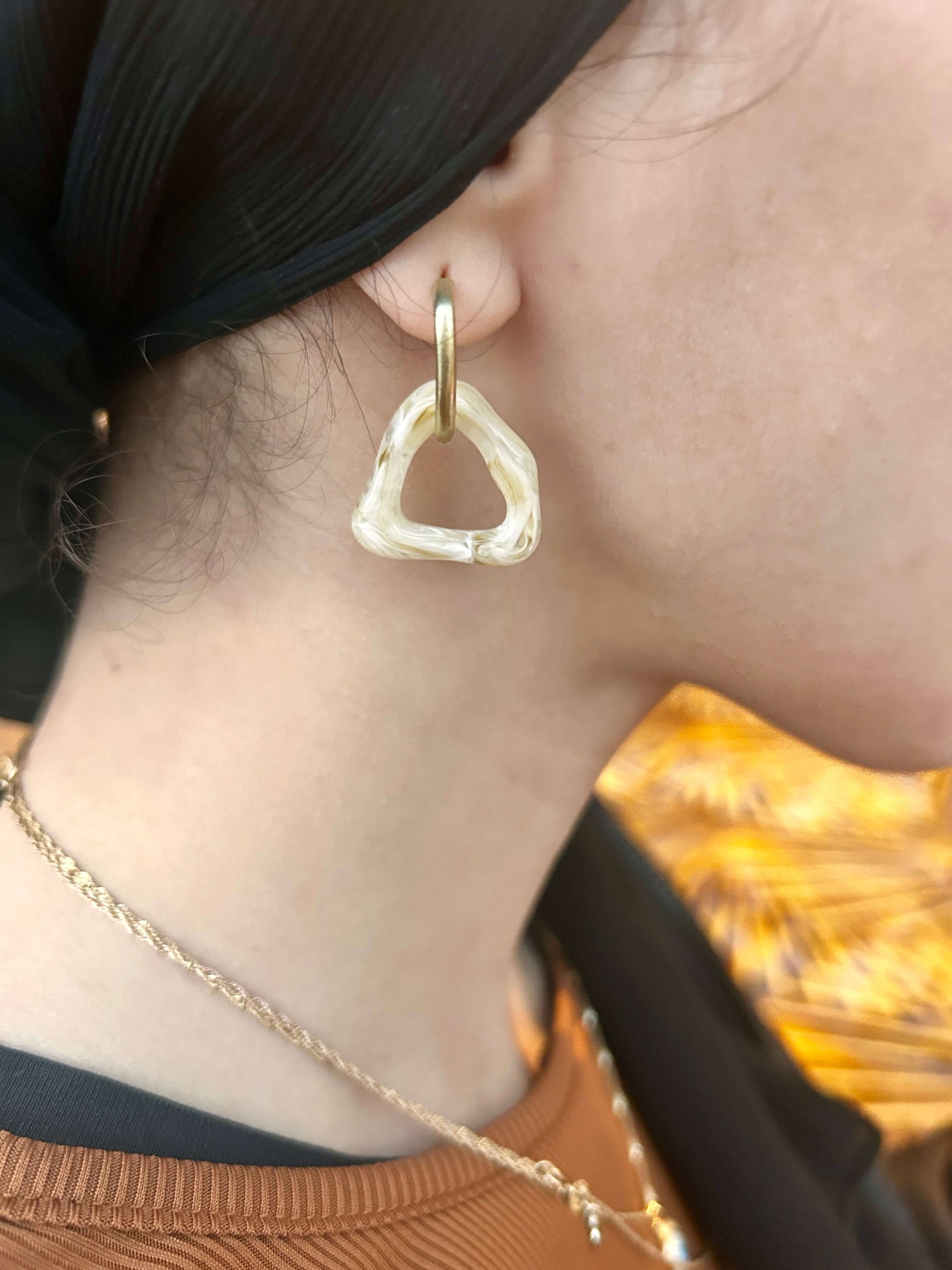 Close up to ear with white abstract asymmetric triangle shape dangle drop resin fashion jewelry earrings - Roulette Safari